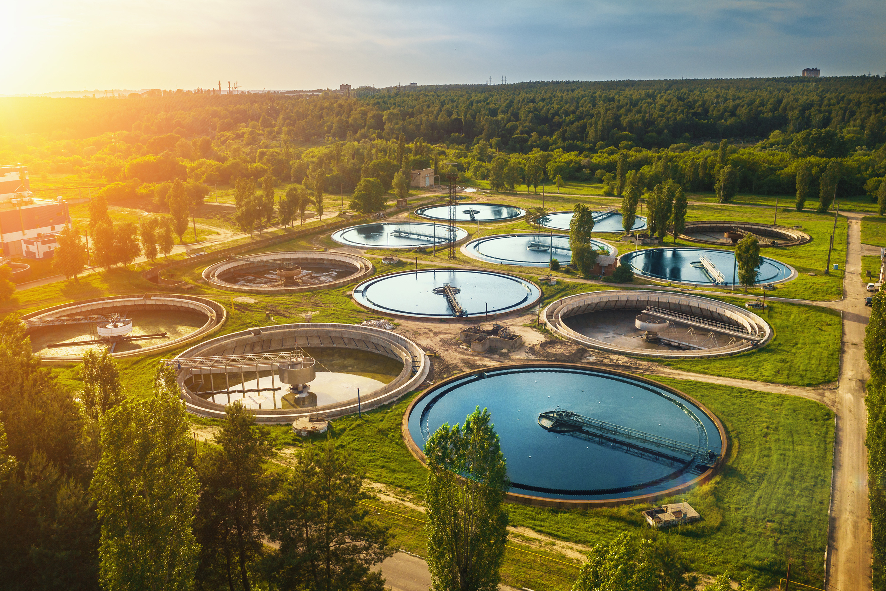 Aerial view of a modern water treatment facility surrounded by nature, representing sustainable infrastructure.