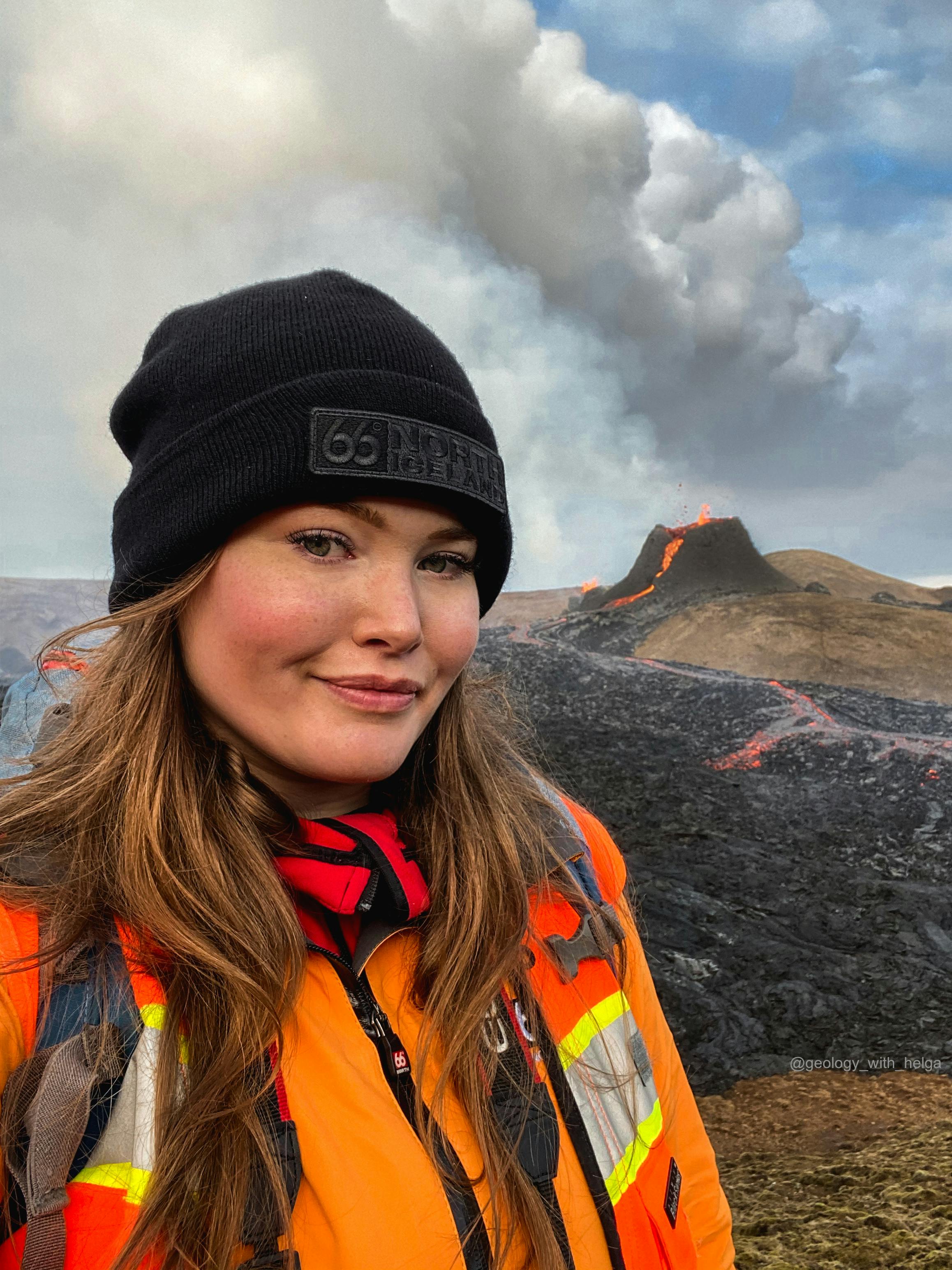 Picture of geologist Helga Kristin Torfadottir in front of an active volcanic eruption