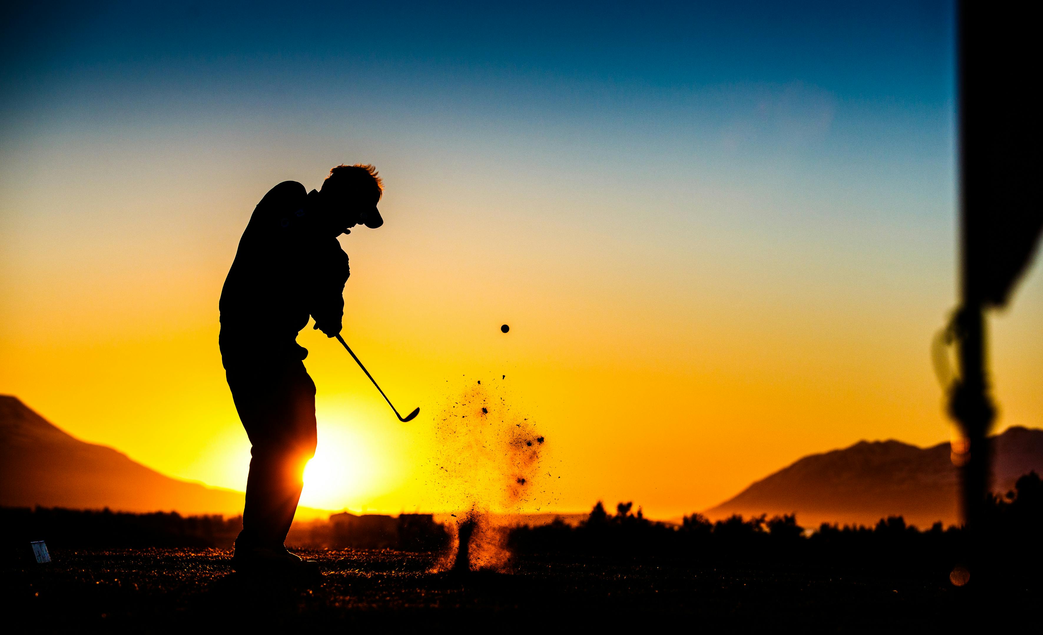 Golfer swinging club in midnight sun during the Arctic Open Golf Tournament in Akureyri, Iceland