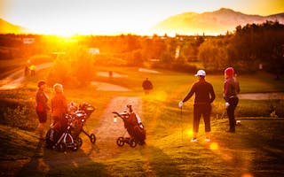 Golfers standing on the course under the midnight sun during the Arctic Open Golf Tournament in Akureyri, Iceland.