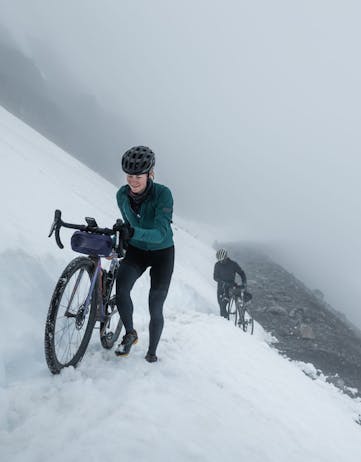 Cyclists walking over snow in the Arna Westfjords Way Challenge