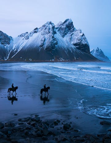 Two horseriders on a black sand beach in Iceland