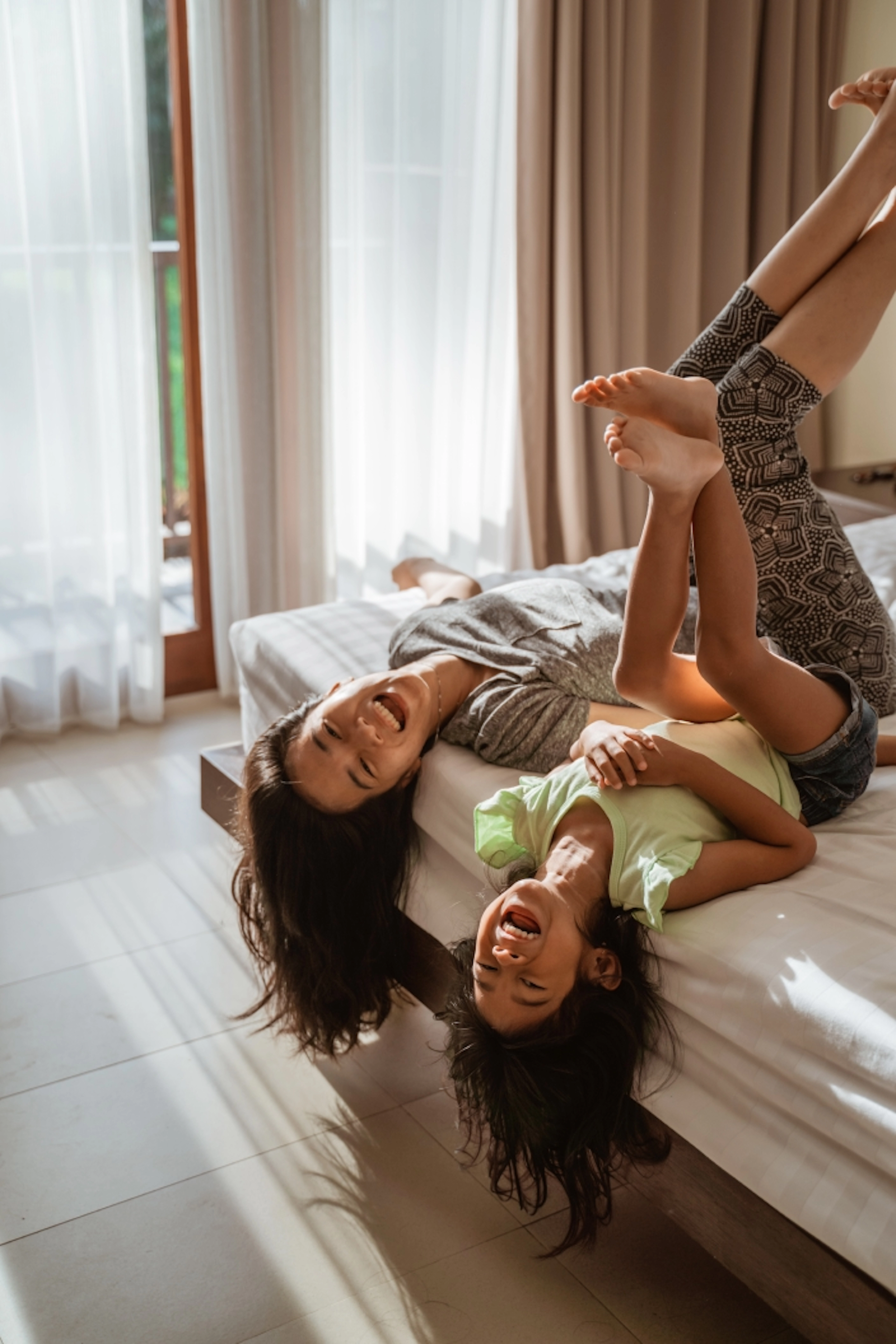 Mãe e filha asiaticas se divertindo em cima da cama