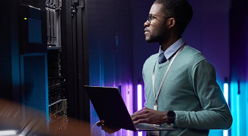 a worker looking at his laptop and desktop computer screen