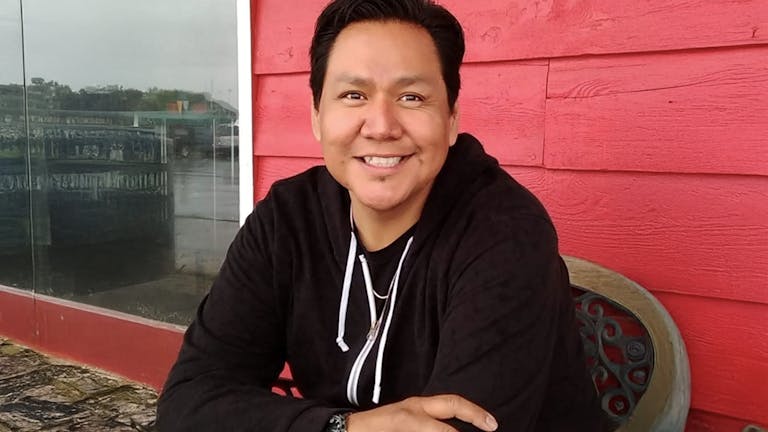 A smiling man sitting on a porch
