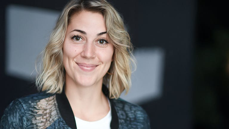 A smiling woman with blond hair looking directly into the camera