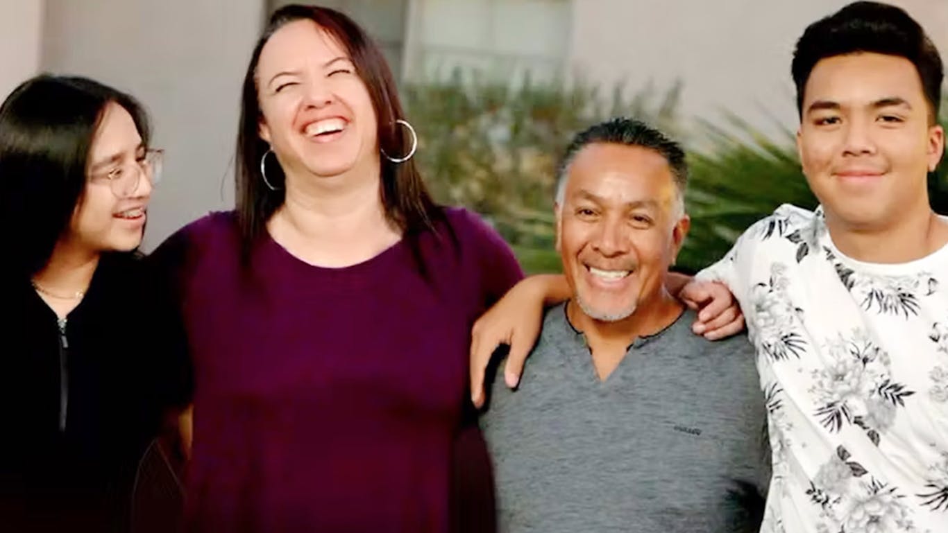 A happy family of four laughing and smiling together