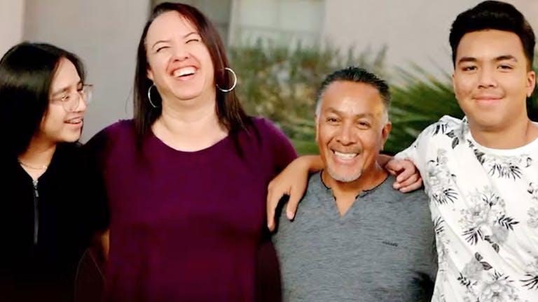 A happy family of four laughing and smiling together