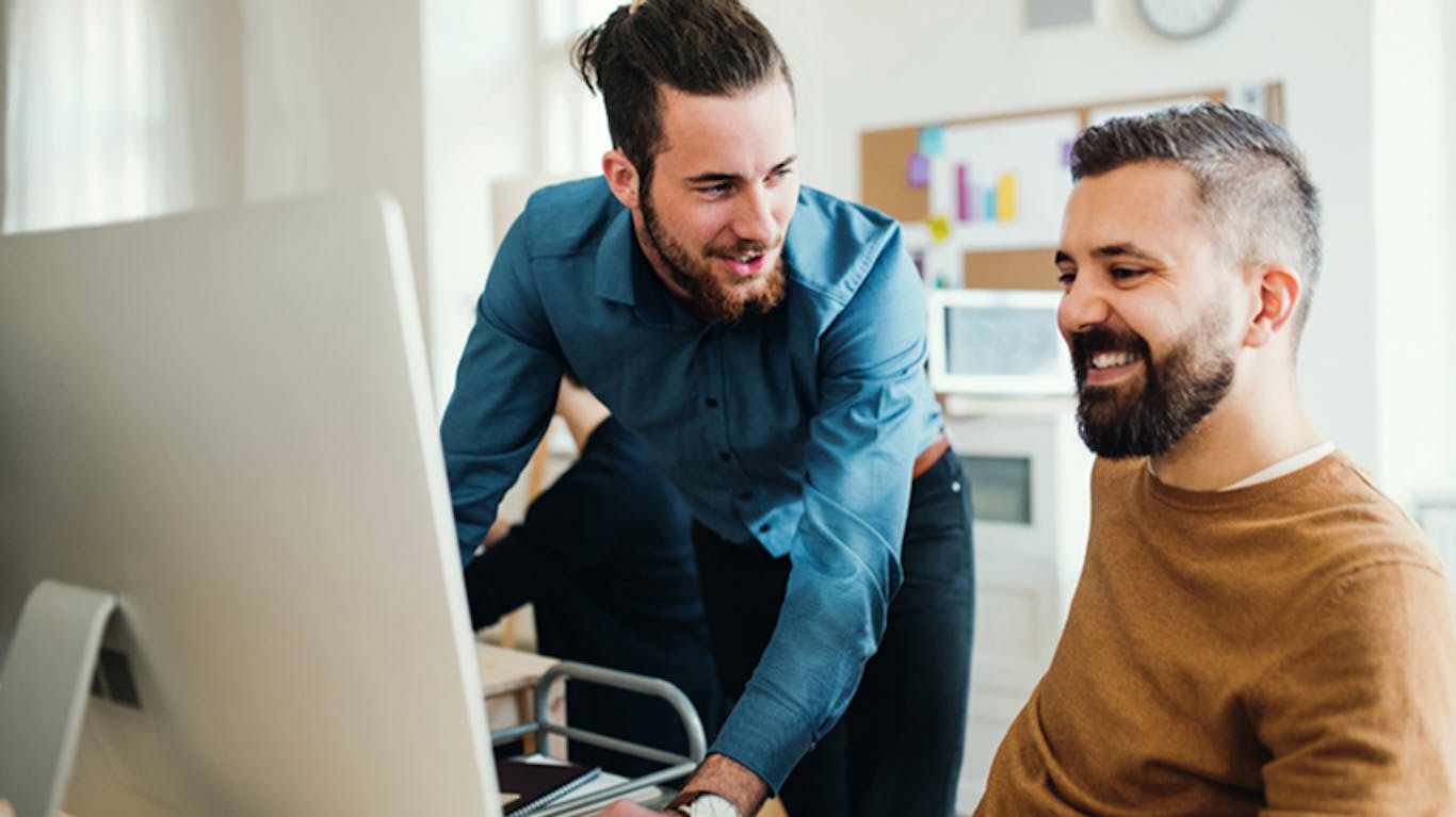 two people collaborating in front of a computer in a work setting