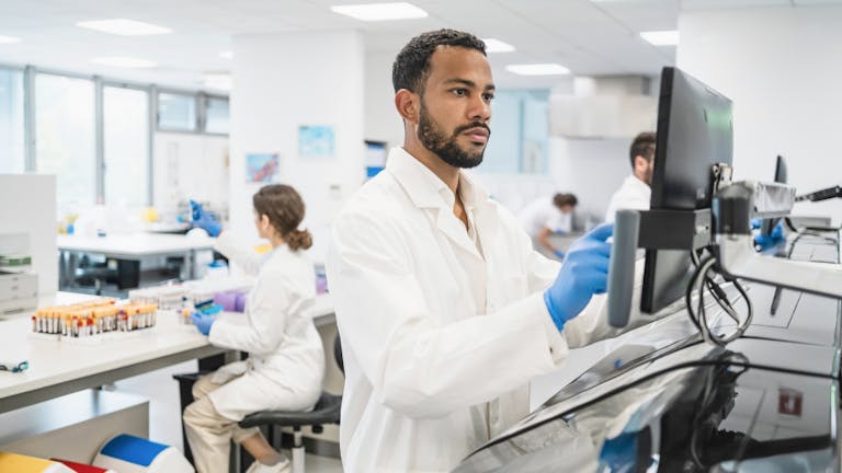 man working in a lab facing a computer screen
