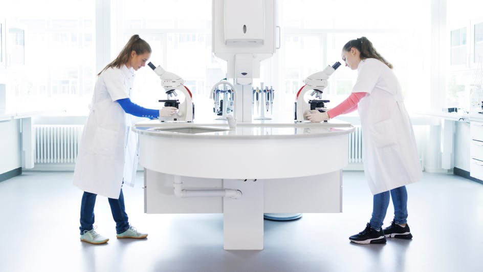 two women working in a lab and using a microscope
