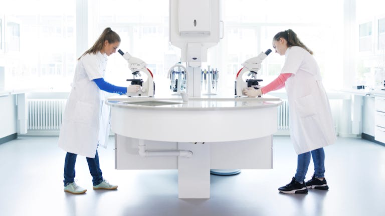 two women working in a lab and using a microscope