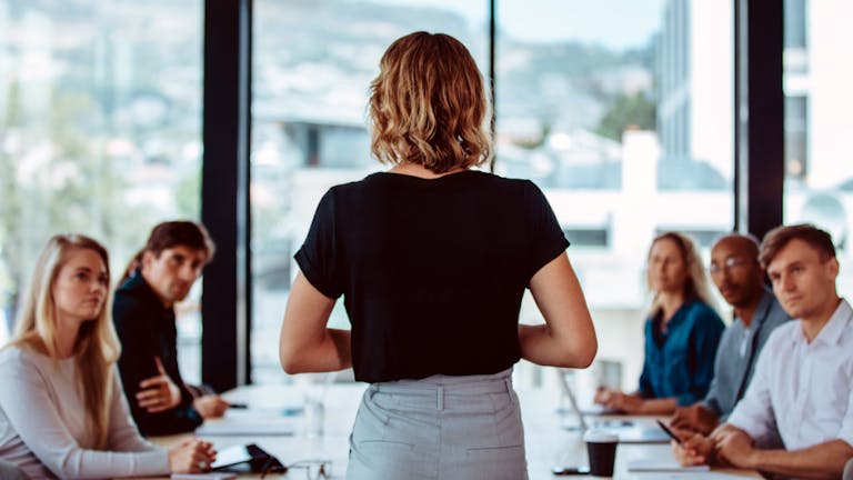 woman facing a group of people in a corporate work setting