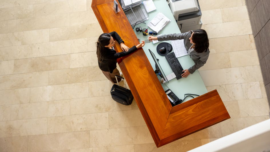 overhead shot of a person handing something to someone behind a desk