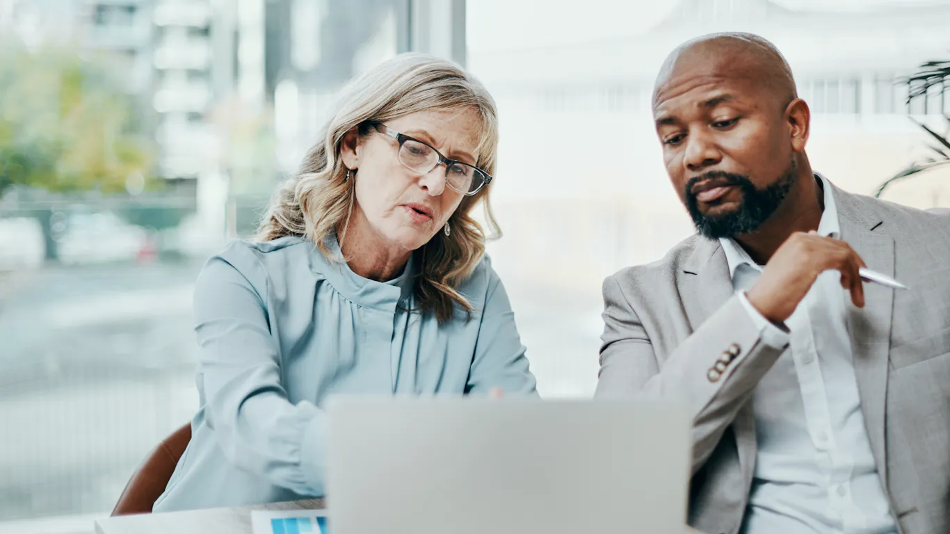 Two people discussing what they see on their computer monitor.