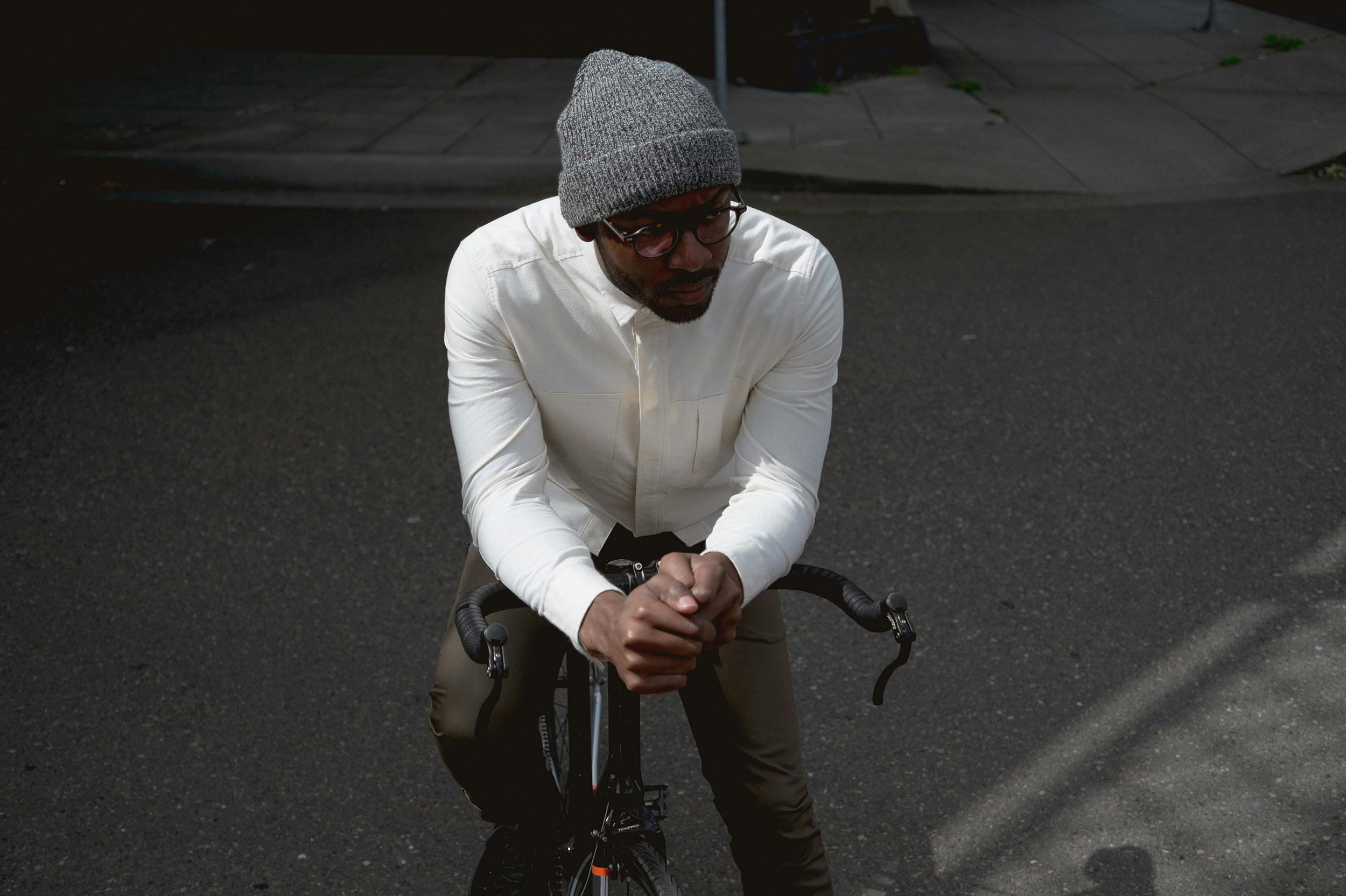 A man leans forward on his parked bicycle.