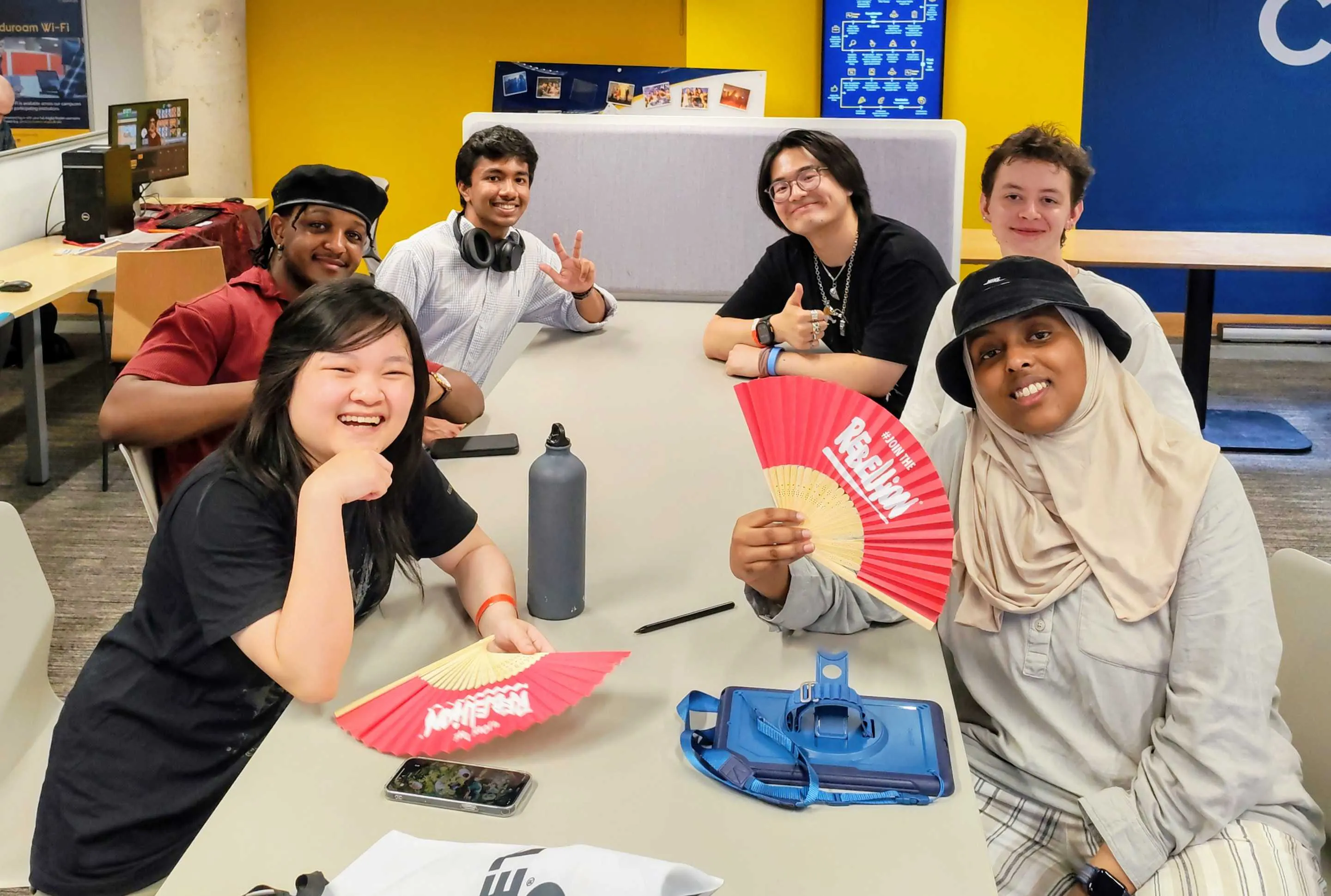 A group of six people sat around a table smiling into the camera.