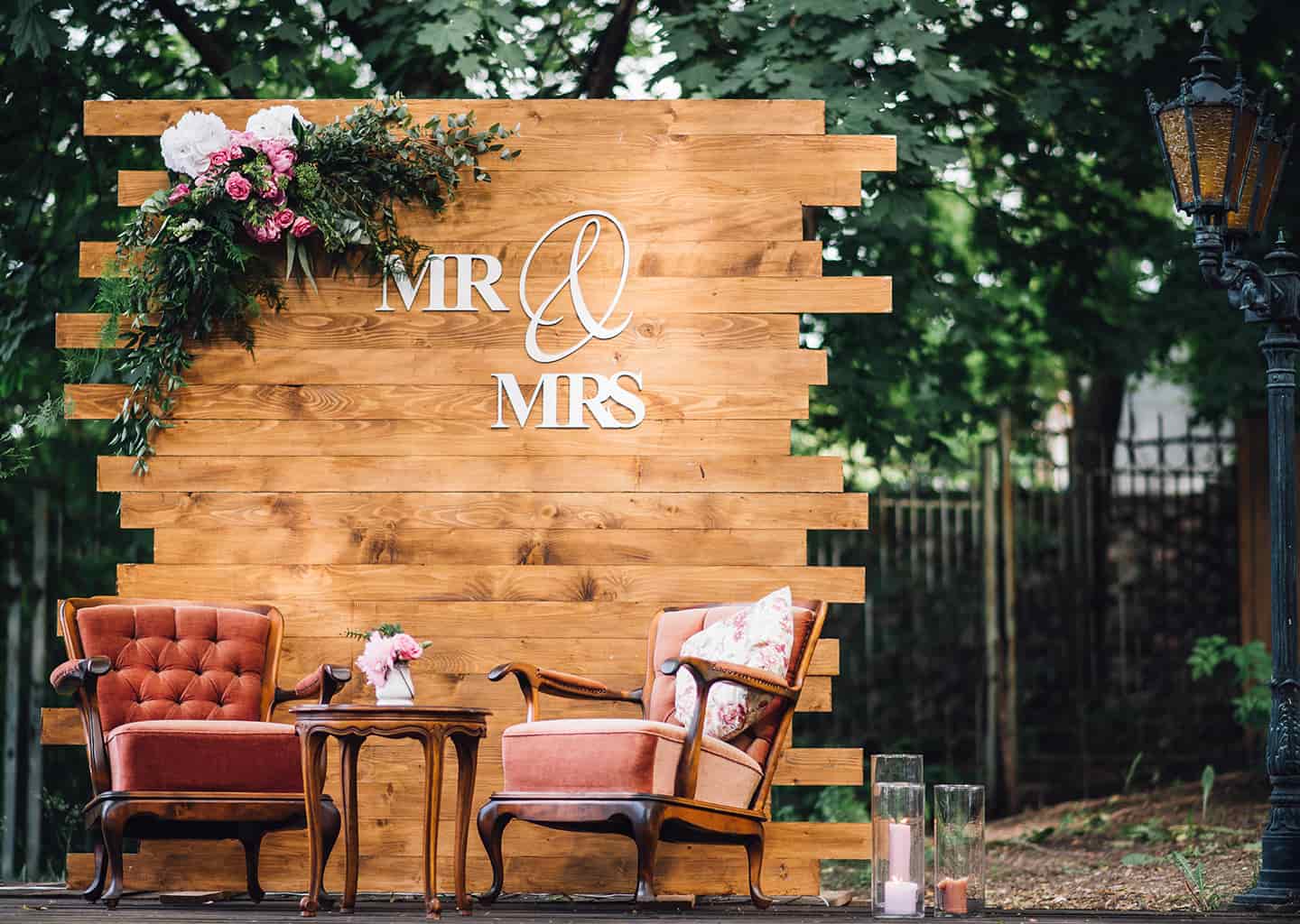 Tahta parçalarından oluşturulmuş ve çiçekler ile süslenmiş dekor önünde iki adet eski koltuk ve koltukların arasında ise küçük bir sehpa bulunuyor. Sehpanın üzerinde vazo içerisinde pembe bir çiçek duruyor.