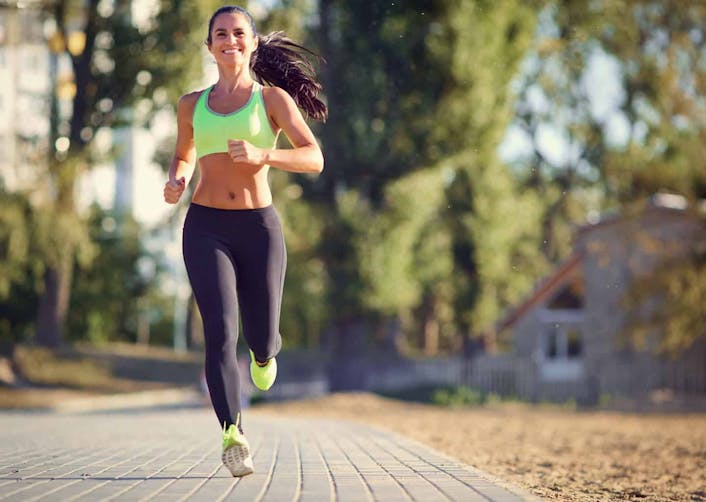 Yeşillik bir alan içerisinde koşu yapan genç kadın gülümsüyor. Kadının üzerinde spor atleti ve tayt bulunuyor. Kadının saçları at kuyruğu şeklinde toplanmış olarak duruyor.