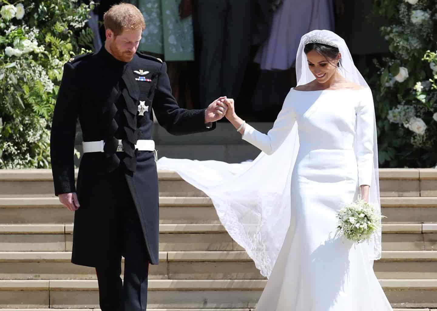 Yakın plan çekimde gelin ve damat merdivenlerden aşağı doğru iniyor. Gelin ve damat el ele tutuşuyor.