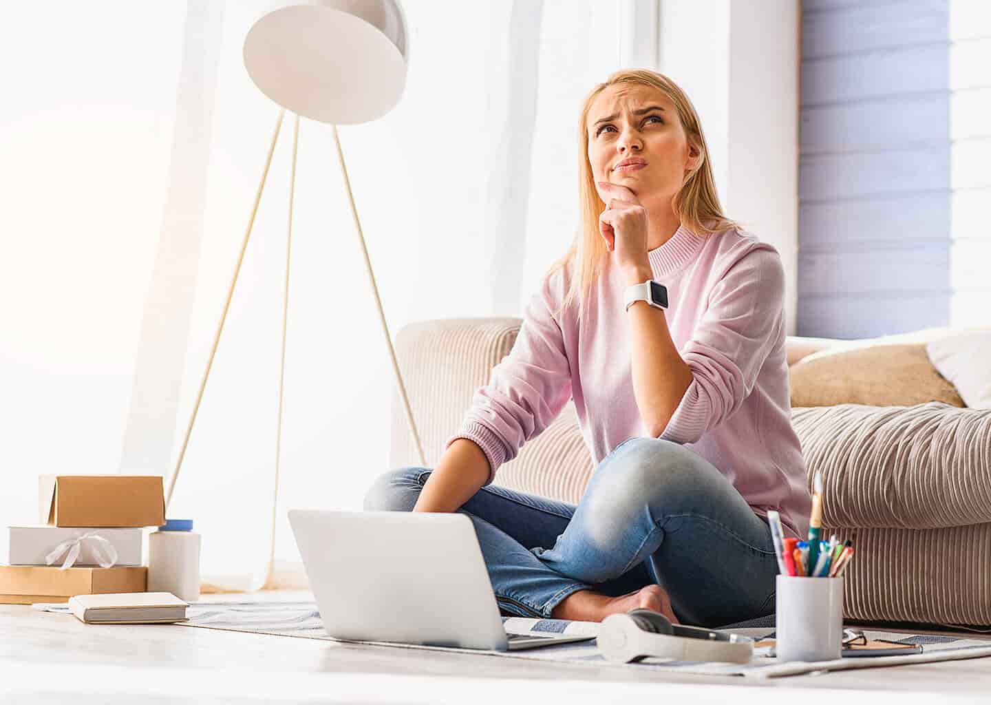 Genç kadın yerde otururken sol elini çenesine koyarak ve sol yukarı bakarak düşünüyor. Kadının önünde dizüstü bilgisayar, renkli kalemler, kulaklık ve kitap duruyor. Kadının arkasında ise kahverengi bir koltuk bulunuyor.