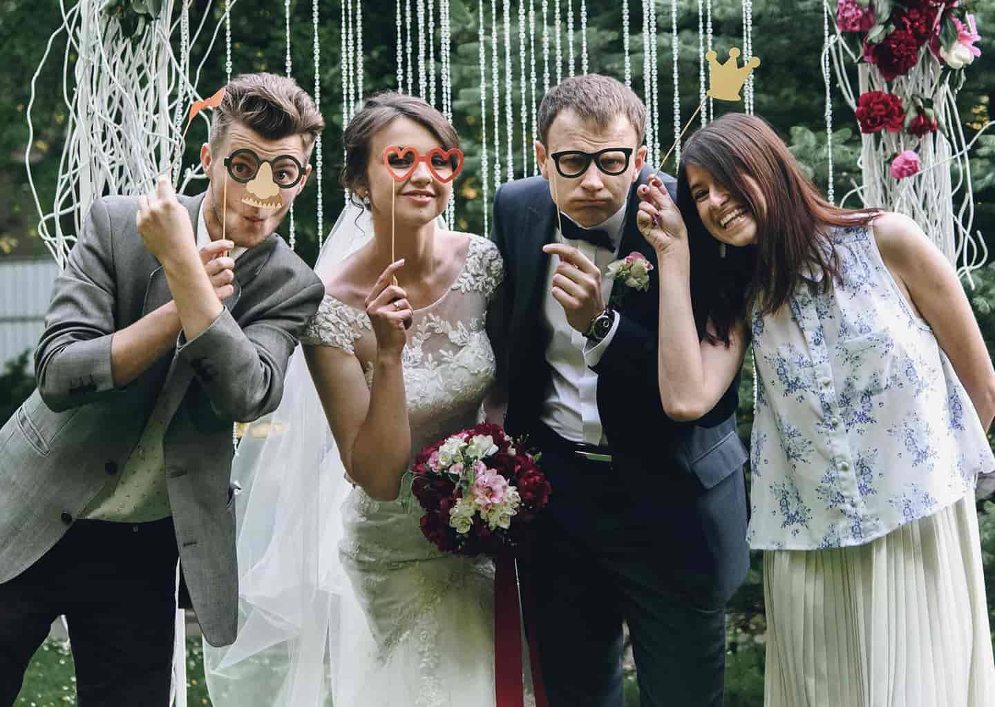 Gelin, damat ve arkadaşları parti gözlükleri takıyor ve gülümseyerek poz veriyorlar.