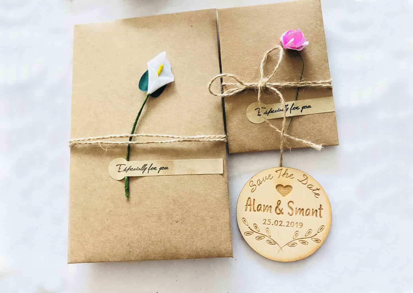 Açık renk arka plan üzerinde; paketlenmiş ve çiçek motifleri ile süslenmiş düğün davetiyeleri bulunuyor.