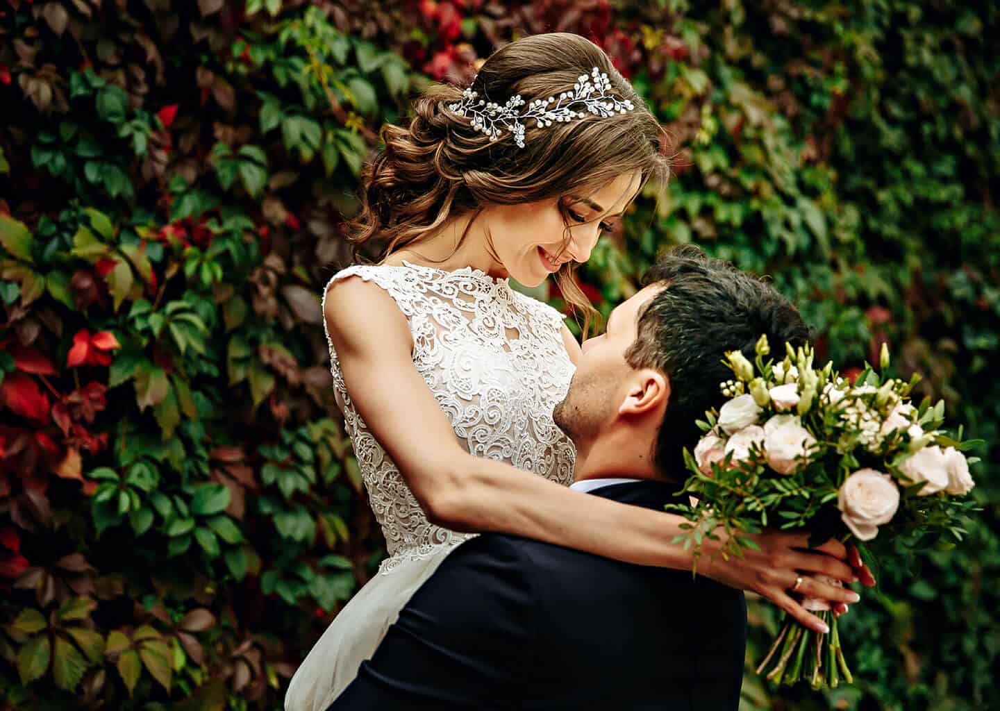 Yeşillik bir arka plan önünde; damat gelini kucağına alarak havaya kaldırıyor. Gelin gülümseyerek damada bakıyor. Gelinin elinde gelin çiçeği bulunuyor.