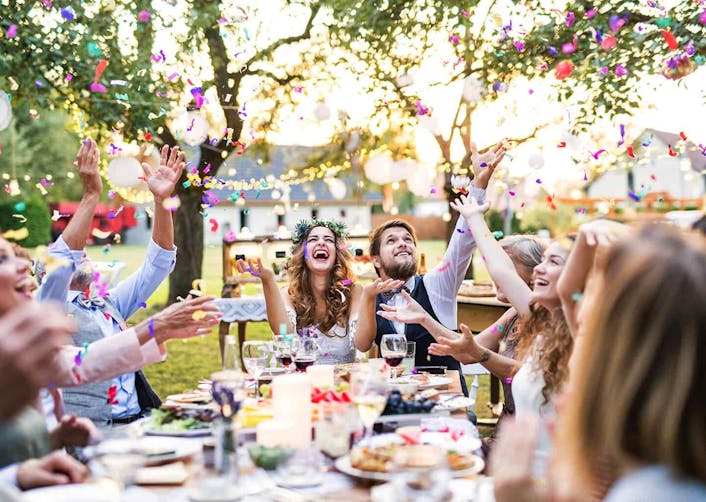 Bahçede bulunan yemek masasında yemek yiyen gelin, damat ve davetliler ellerine havaya kaldırarak gülümsüyor ve kutlama yapıyorlar. Etrafta konfeti parçaları uçuşuyor.