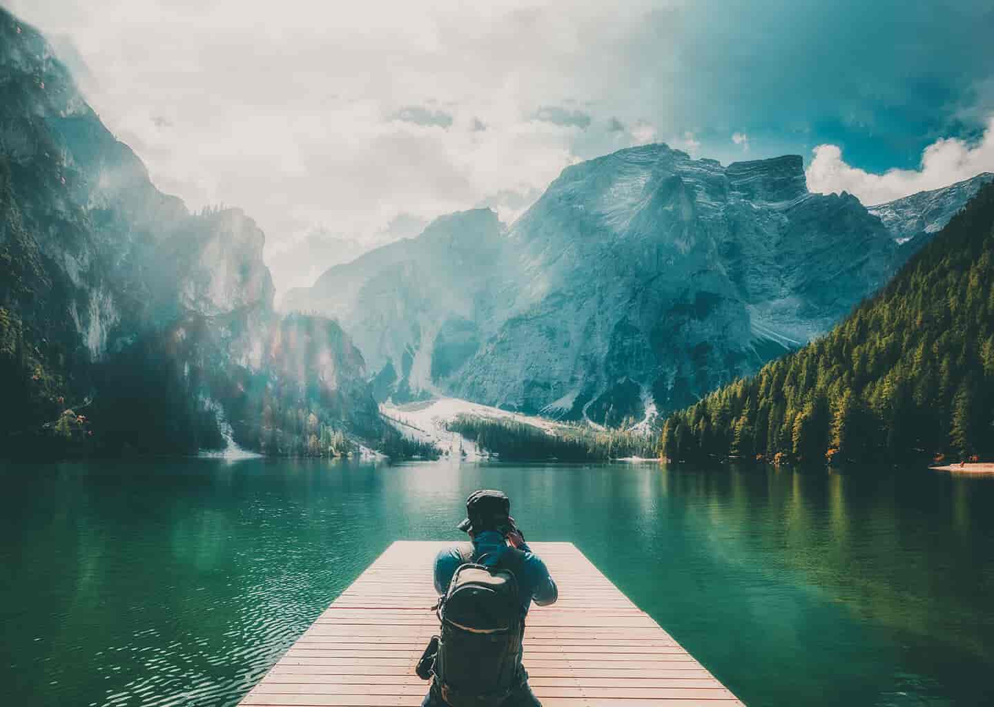 Arkası dönük olan adam, karşısında bulunan deniz, dağ ve doğa manzarasını çekiyor.