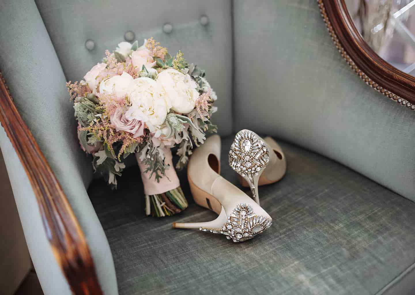 Gri ve eski olan tek kişilik bir koltuk üzerinde gelin çiçeği ve gelin ayakkabısı bulunuyor.