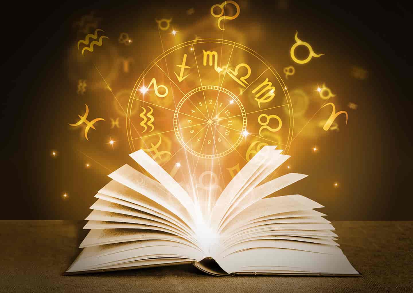 Masa üzerinde duran ve sayfaları açık olan kitabın içerisinden ışıltı yükseliyor. Işıltıların üzerinde ise altın renkli burç sembolleri duruyor.
