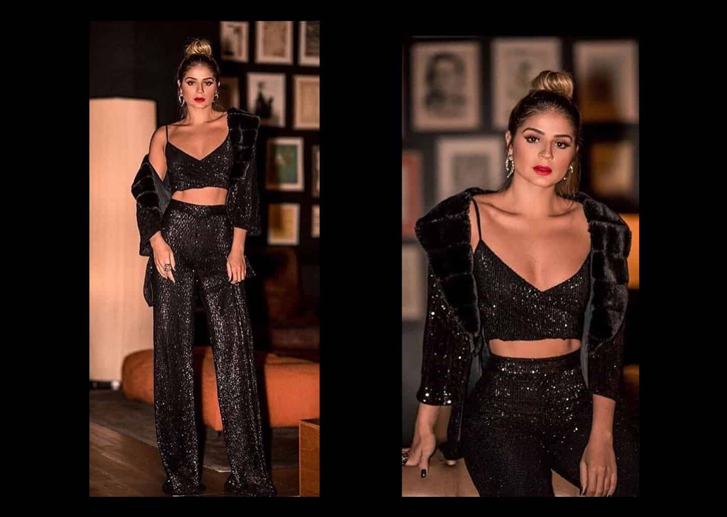 Genç kadının üzerinde parlak siyah büstiyer, ispanyol paça pantolon ve ceket bulunuyor.