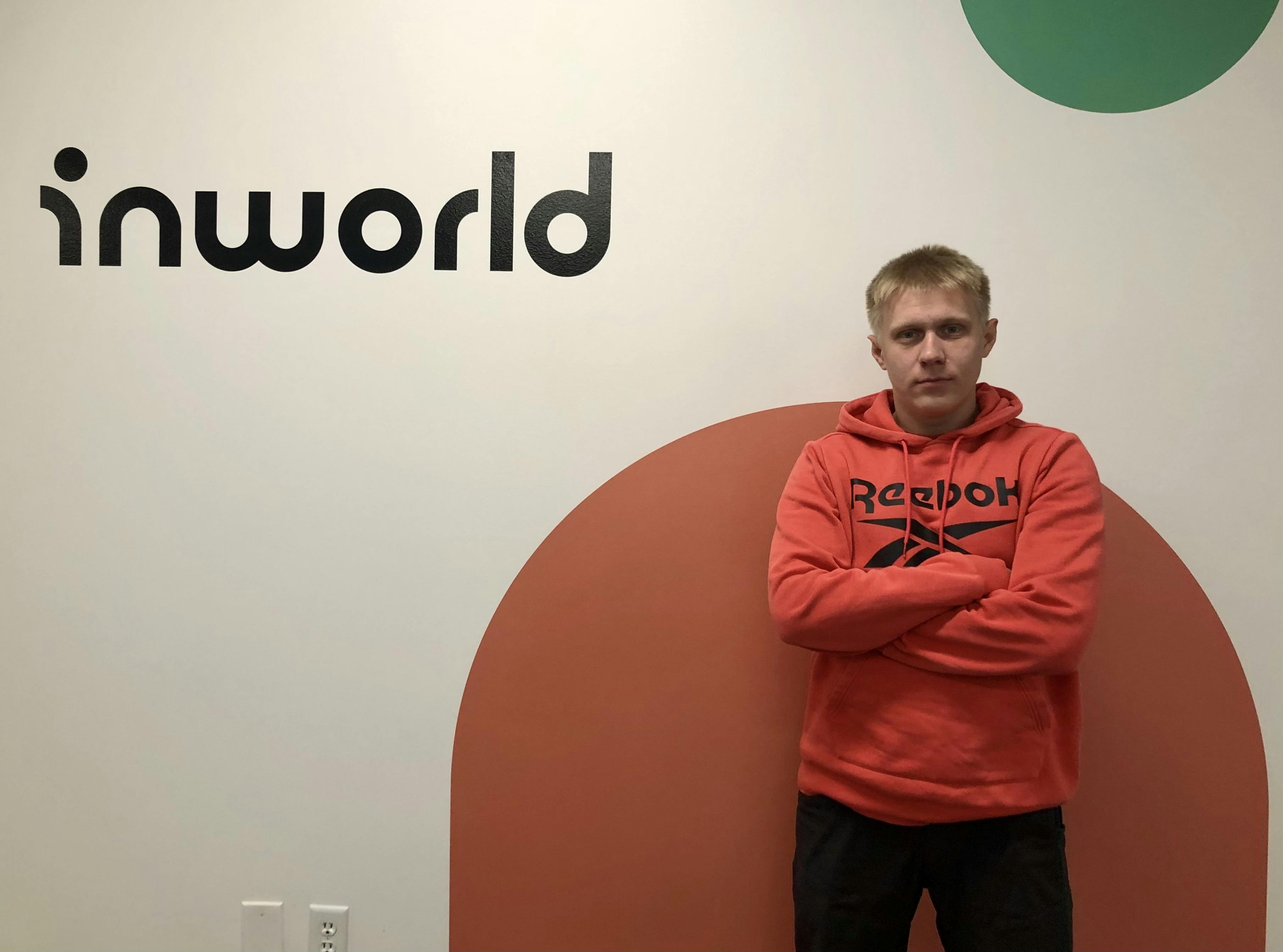 A man is standing in front of the wall with Inworld logo on it