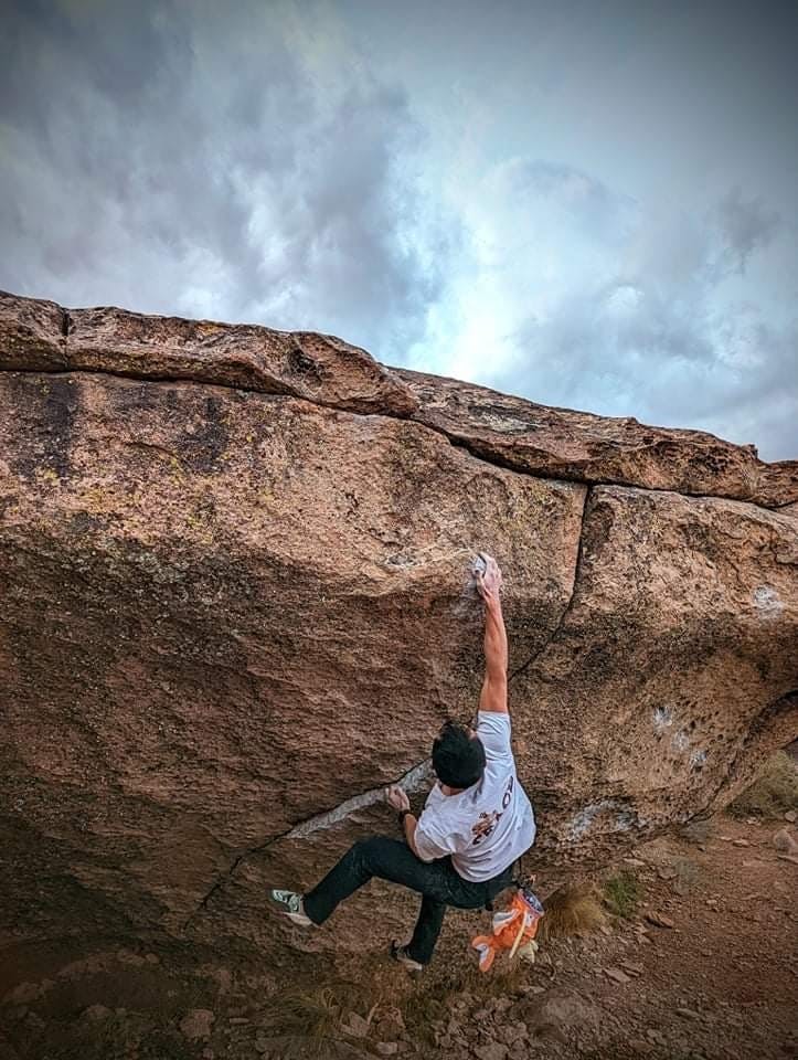 Alex hanging from a rock without ropes