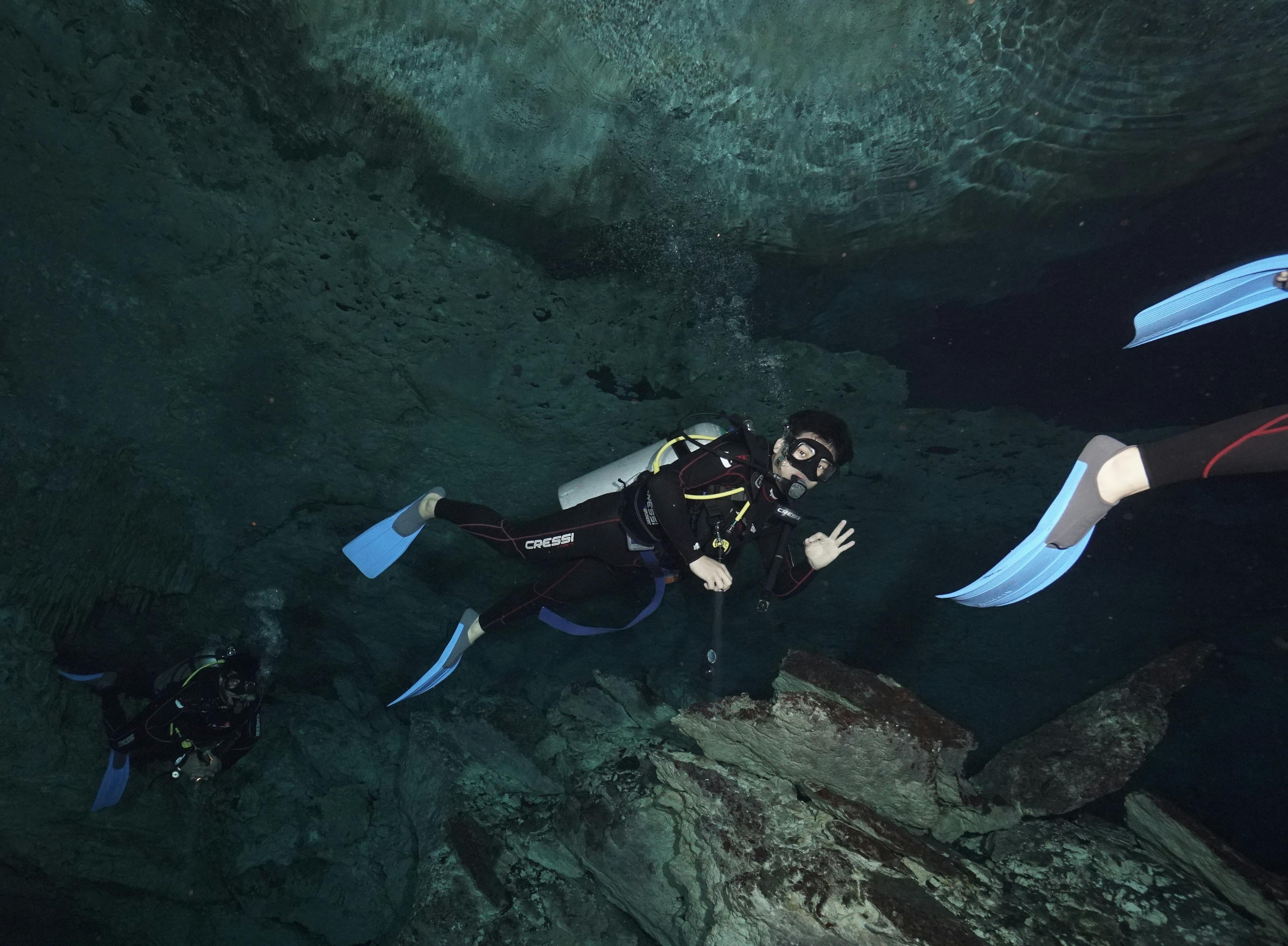 The man is diving deep in the ocean and showing ok sigh. 