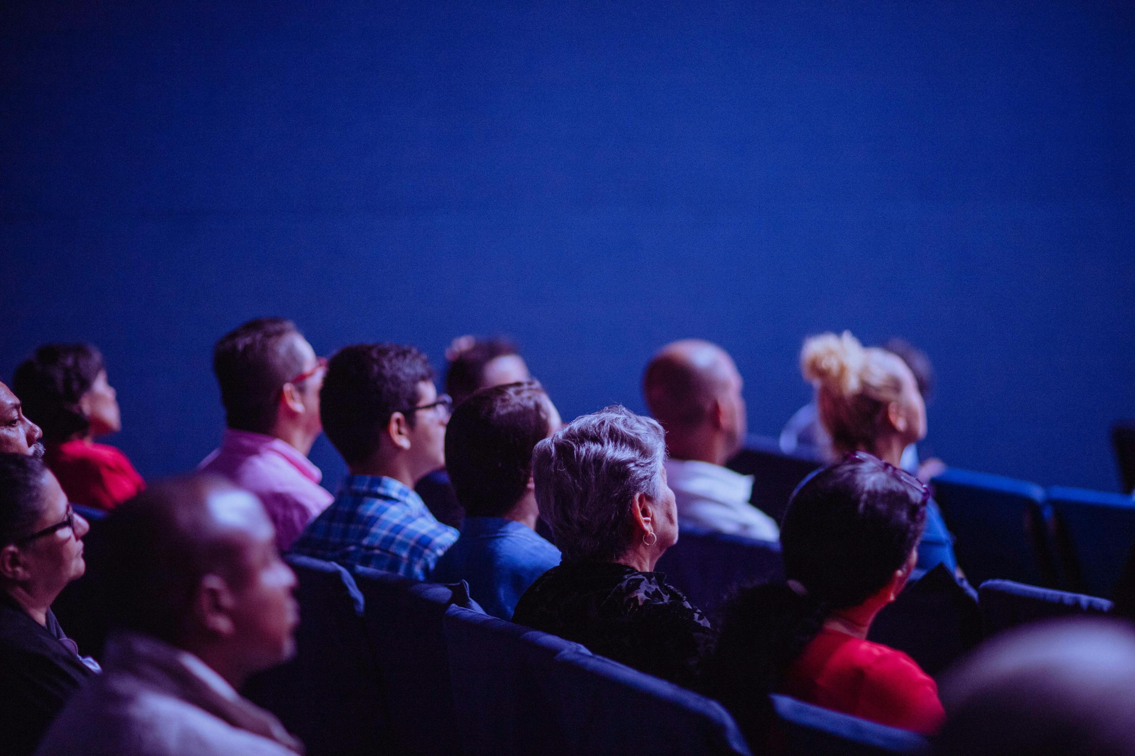 A photo of a group of people watching a movie to represent the film industry's connection to transmedia storytelling that transmedia franchises engage in.