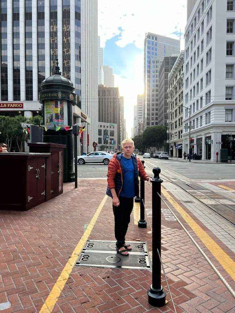 A man is standing on the street and looking into the camera