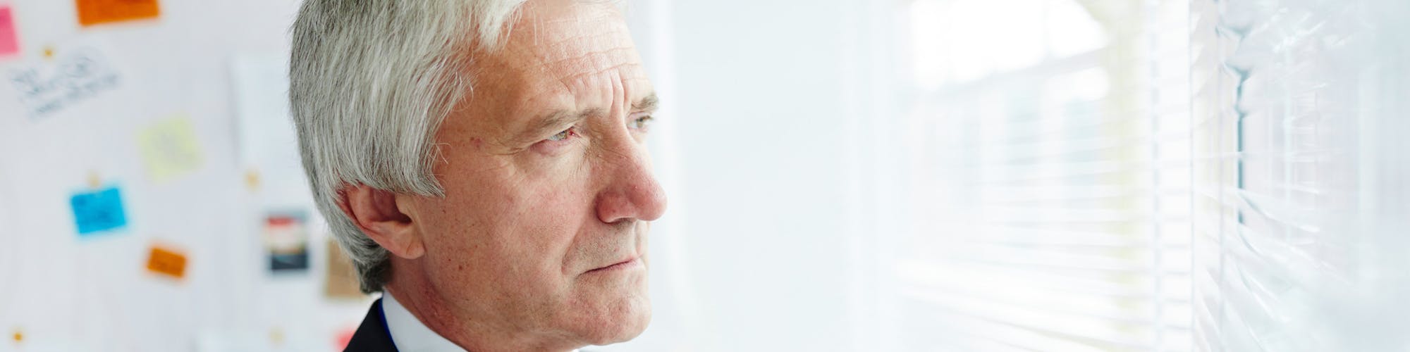 Nachdenklicher Geschäftsmann, der aus dem Fenster sieht