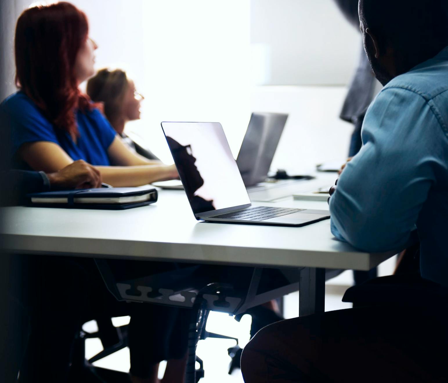 People sitting at table with laptops looking out a window