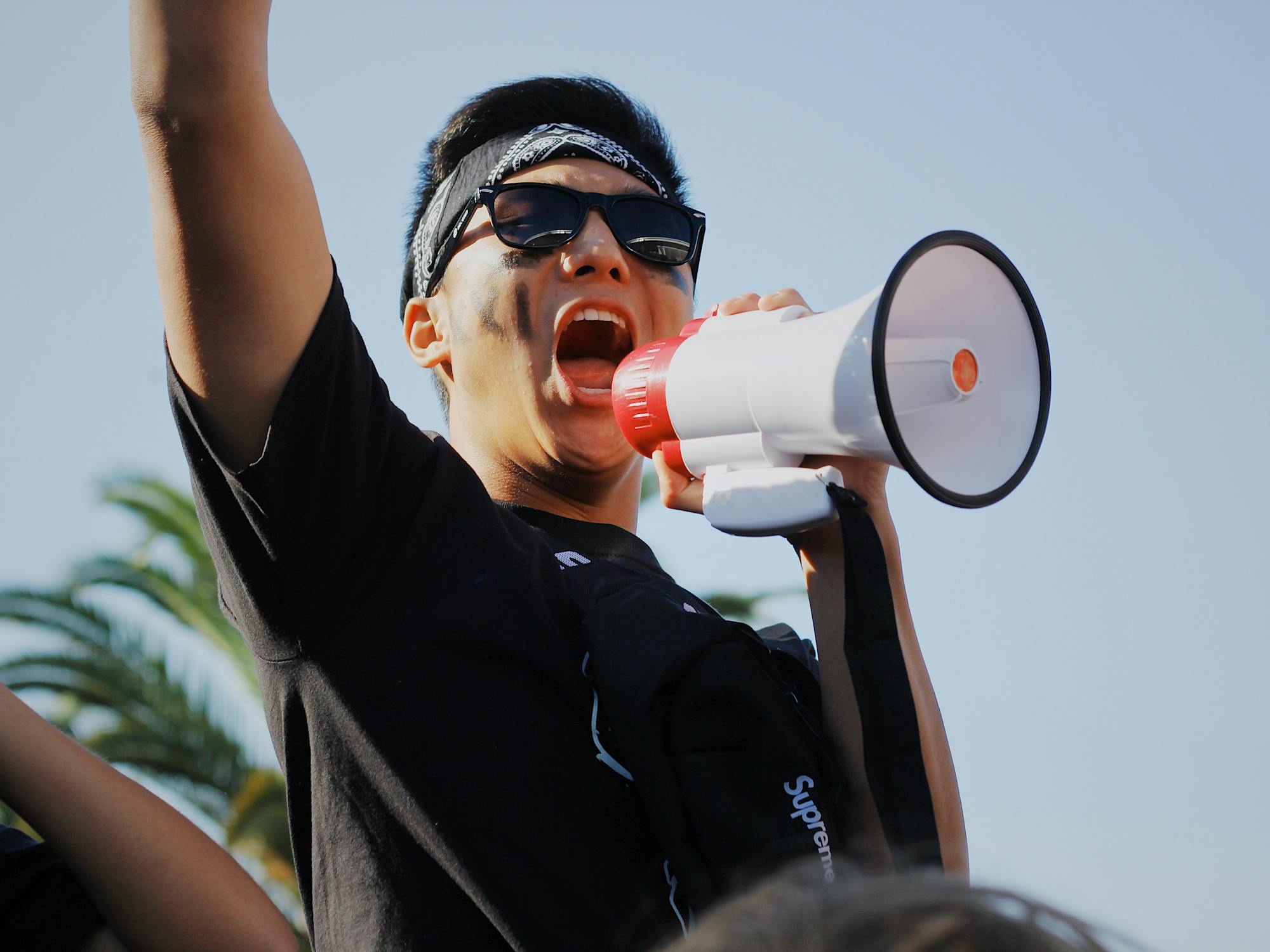A young man throws his arm into the air as he hollers into a megaphone