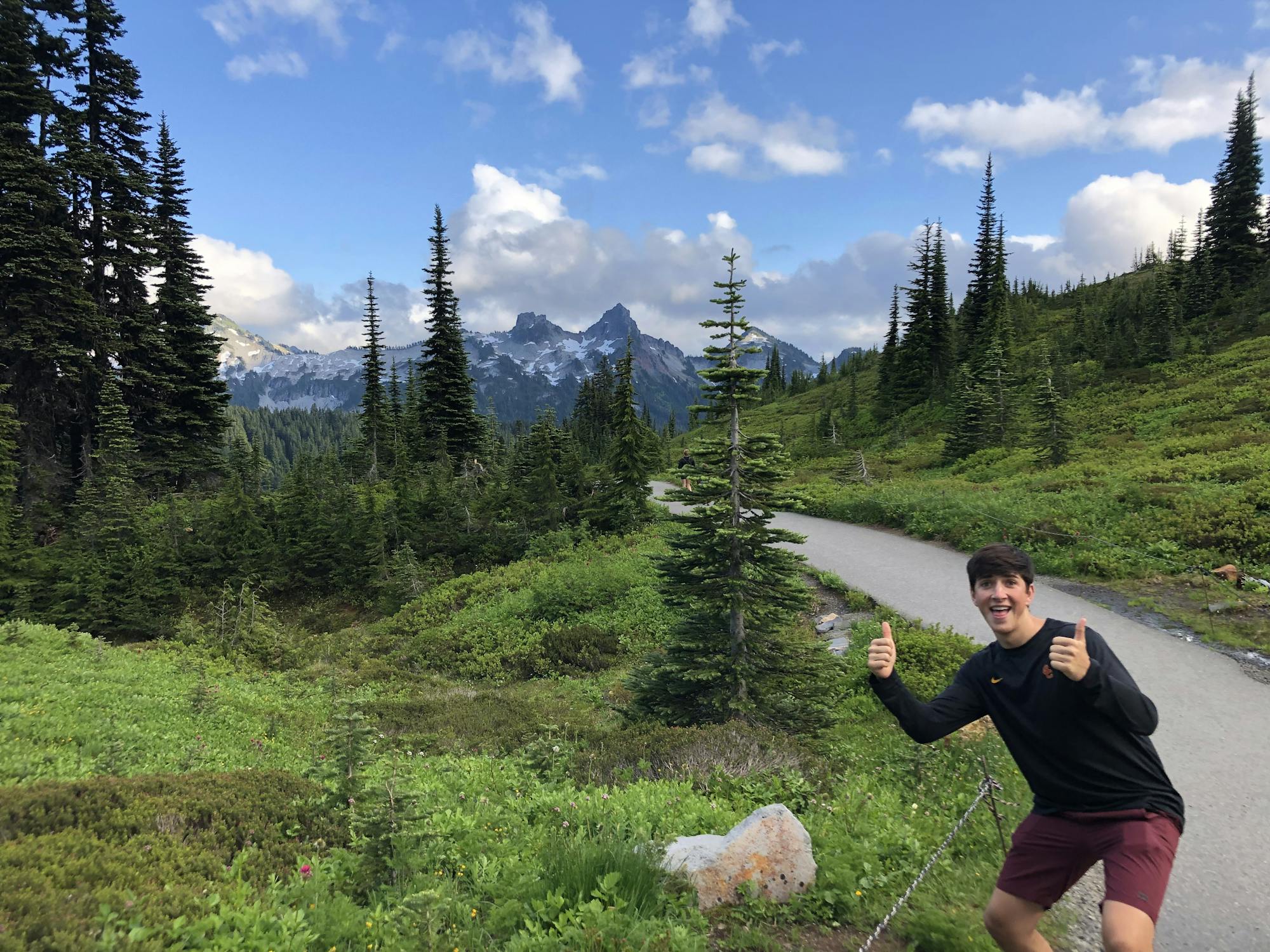 Young man poses out in nature with mountains in the background