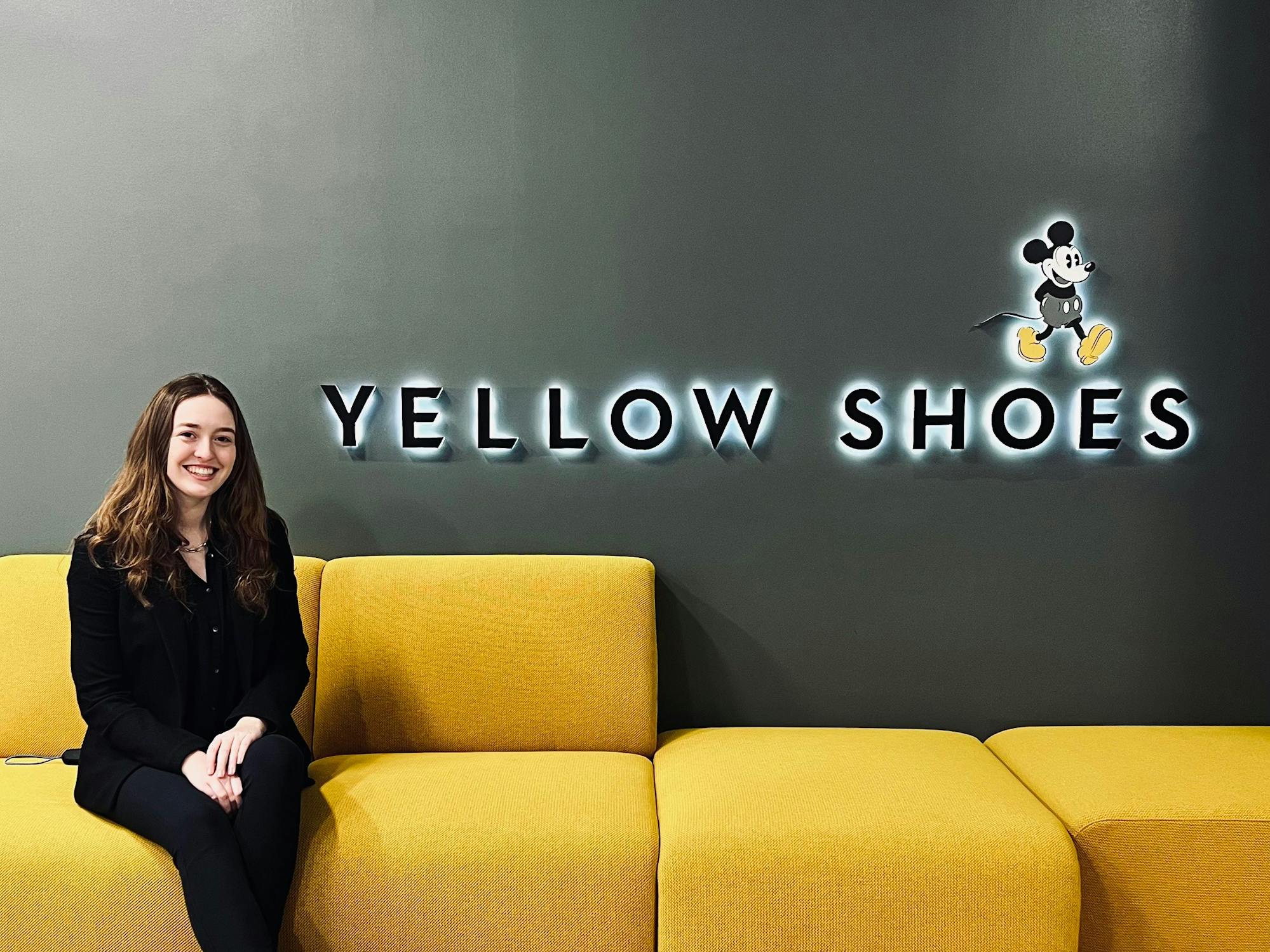 A person on a yellow couch with the signage Yellow Shoes and Mickey Mouse 