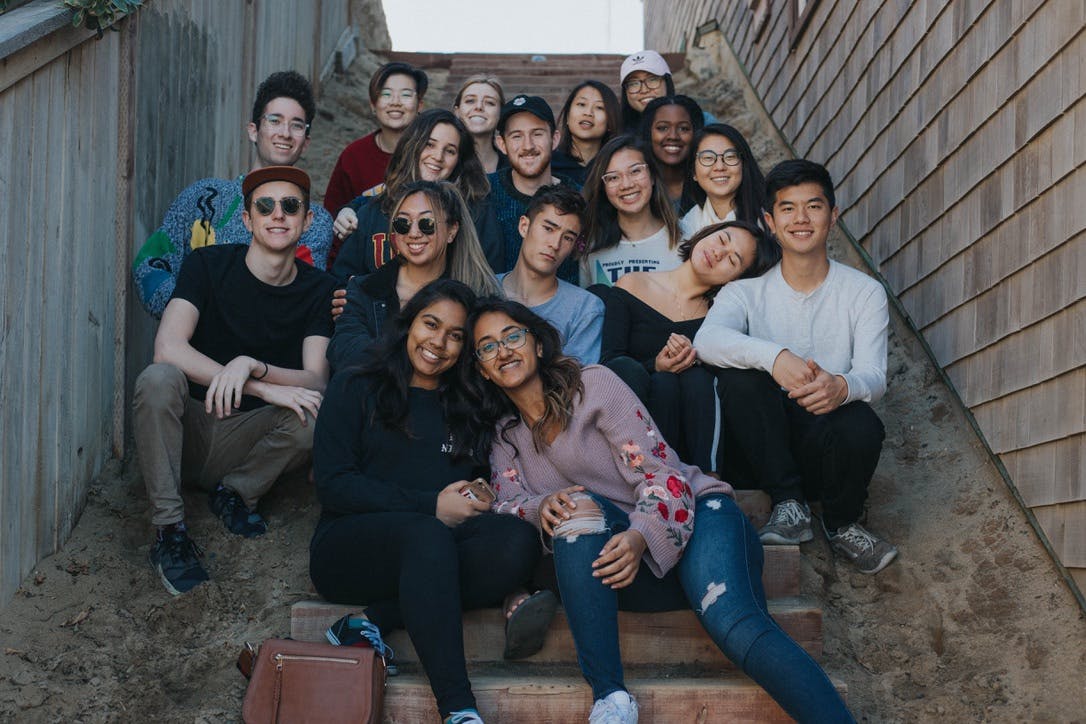 Group of students smiling while sitting in narrow outdoor stairway