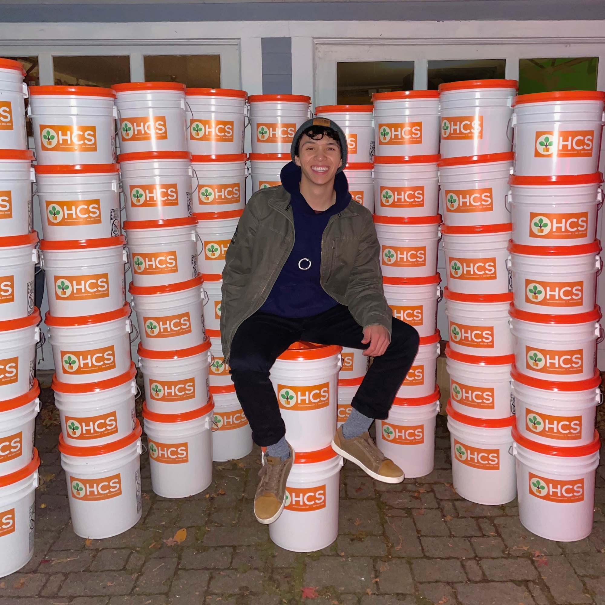 Ben Wan sits surrounded by stacked buckets.