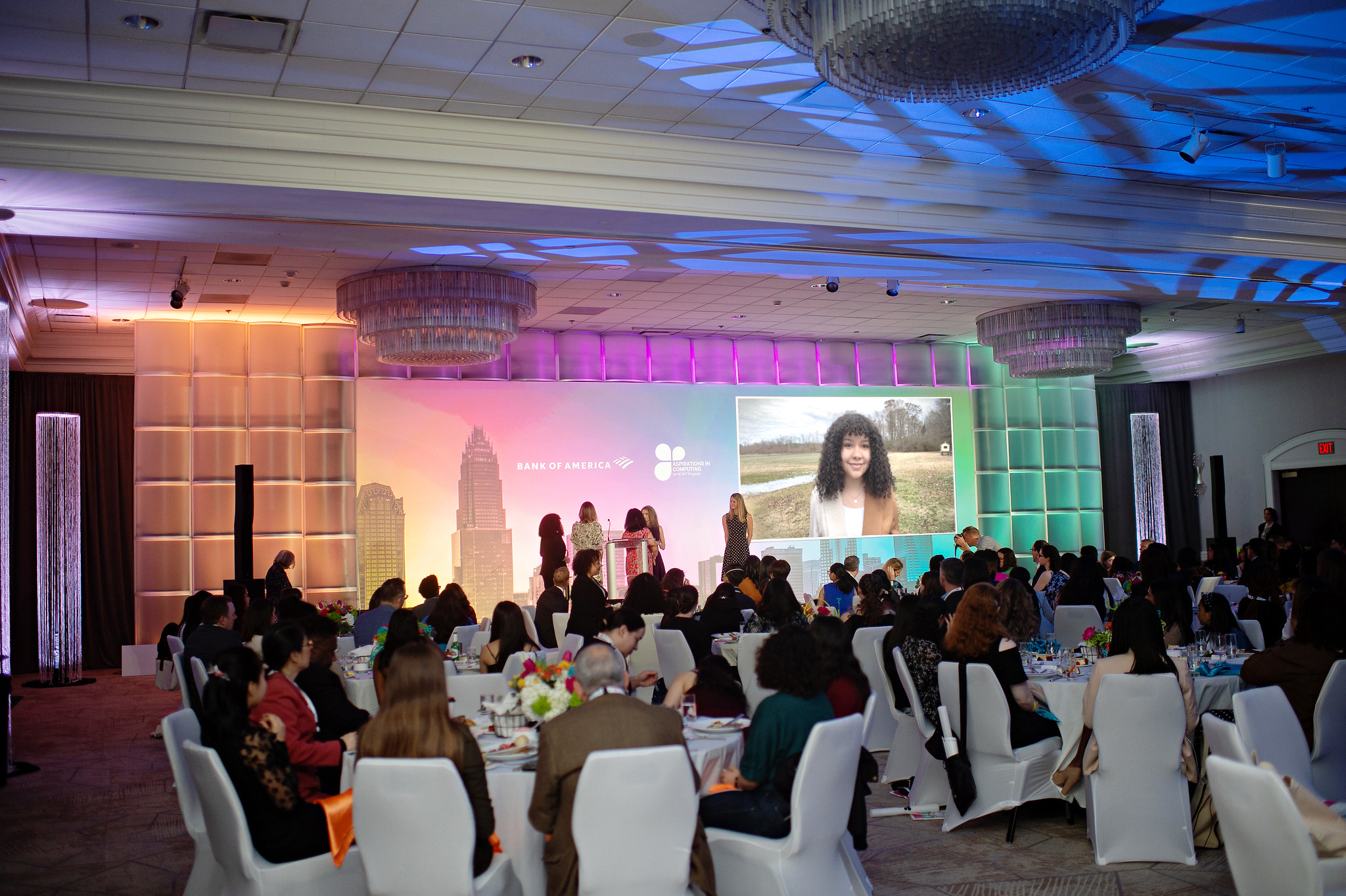 Wide shot of a colorful stage where a video is being projected. 