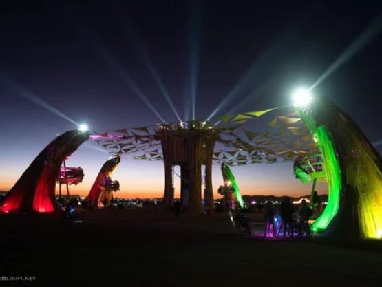A large-scale sculpture in five parts, connected by interlocking triangles, lights up the night with its colored lights