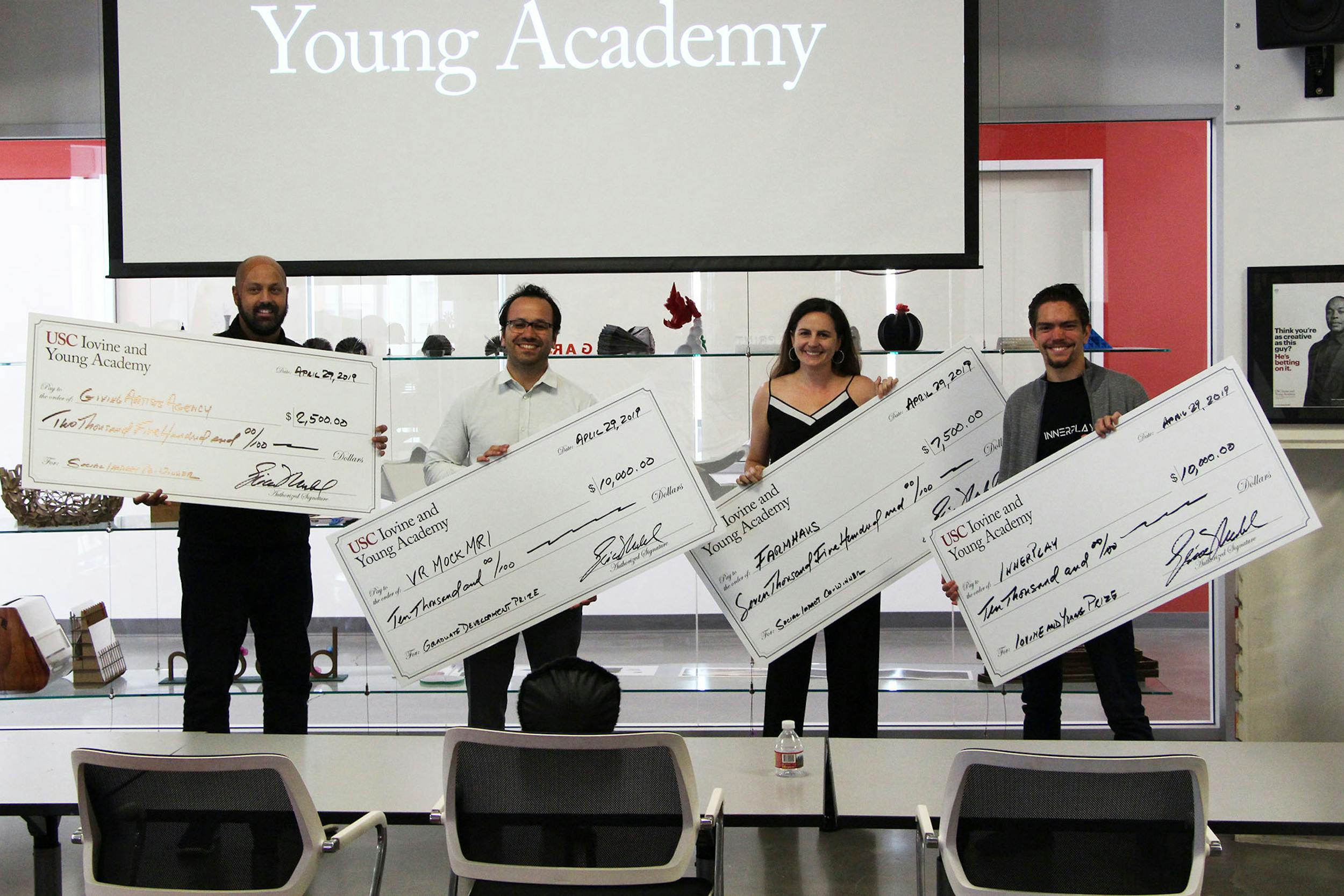 4 students each holding giant checks