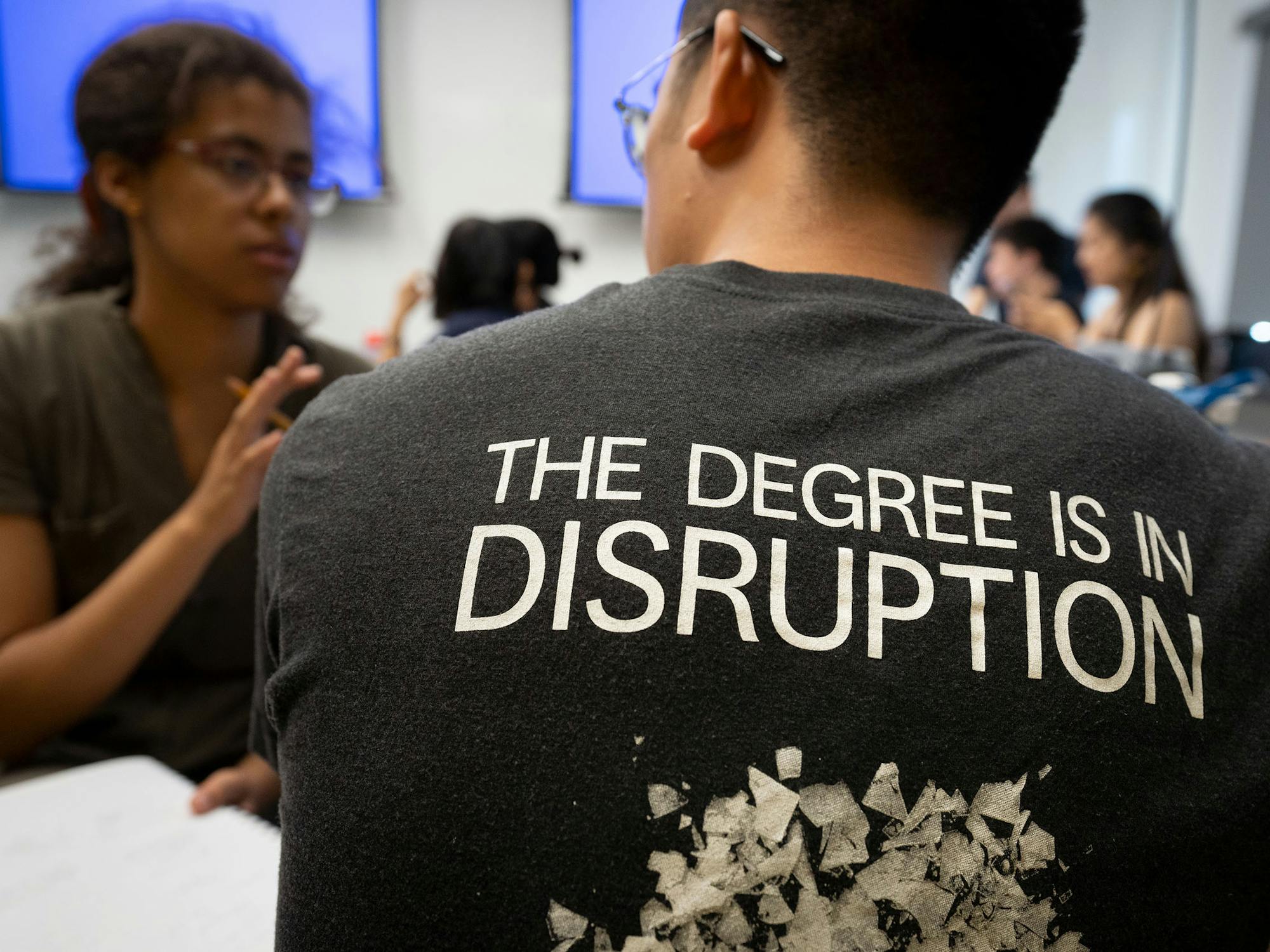 Two students, shirt says the degree is in disruption.