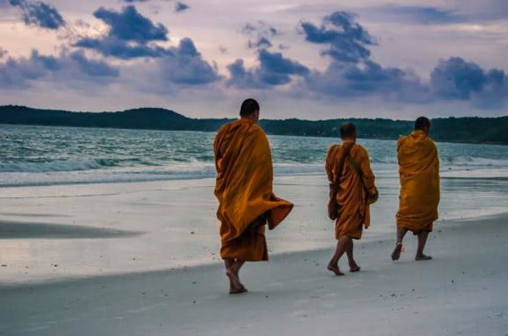 Monks walk across a beach